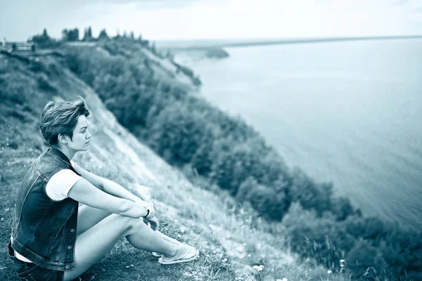 寂寞年轻美丽的年轻女子坐在河岸边的肖像 — 图库照片