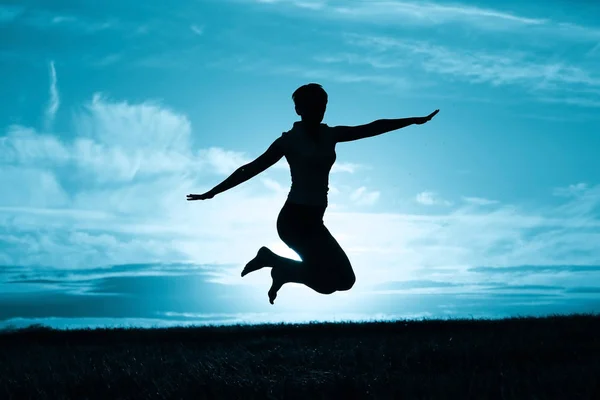 夕焼け空 幸福という概念に対して屋外ジャンプの若い女性のシルエット — ストック写真