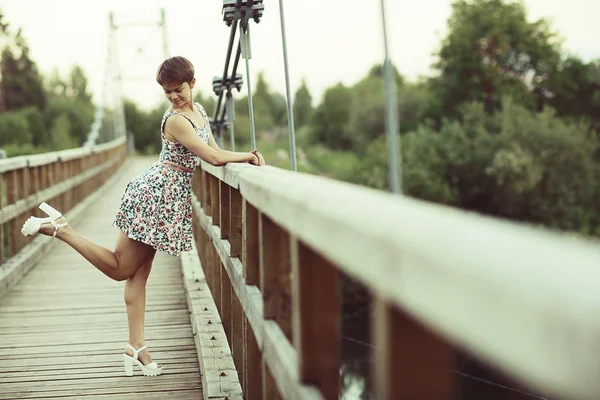 木造の橋 素朴なスタイルの短い夏のドレスの若い美しい女性の肖像画 — ストック写真