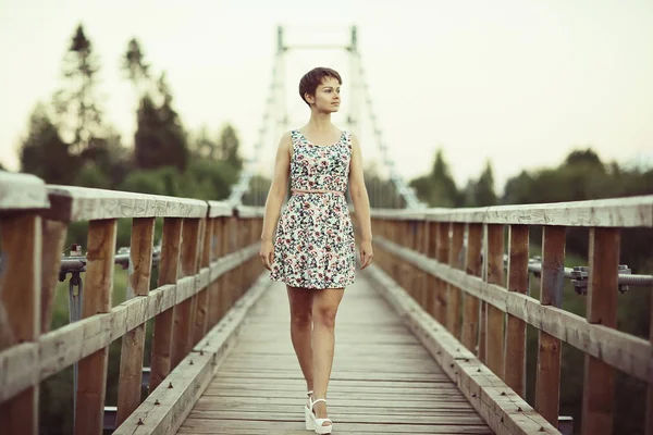 木造の橋 素朴なスタイルの短い夏のドレスの若い美しい女性の肖像画 — ストック写真