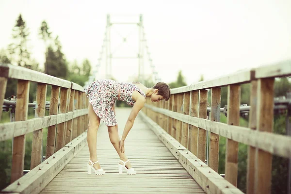 木造の橋 素朴なスタイルの短い夏のドレスの若い美しい女性の肖像画 — ストック写真