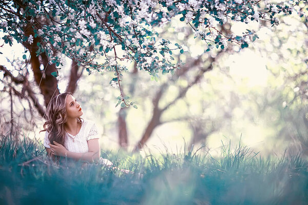 Portrait of young beautiful woman in a spring blooming park, apple blossom