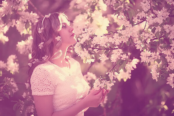 Portrait of young beautiful woman in a spring blooming park, apple blossom