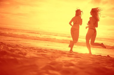 mutlu aşıklar kumlu plajda, gün batımı görünümü siluetleri. Yeni evliler ve denizde resort balayı. 