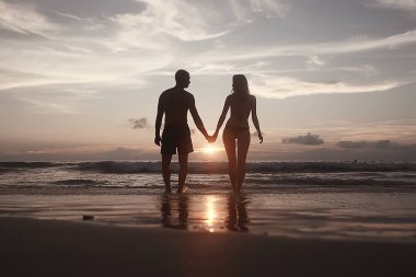 mutlu aşıklar kumlu plajda, gün batımı görünümü siluetleri. Yeni evliler ve denizde resort balayı. 