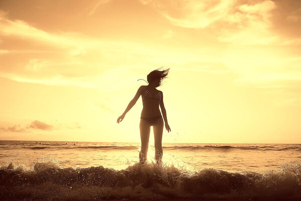 happy young woman is having fun and jumping on beach, concept of freedom and summer vacation