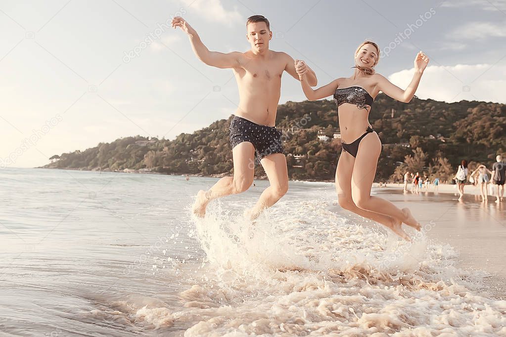 happy love couple jumping in sea waves, sports activity, summer vacation