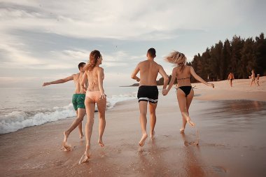kumsalda, çalışan dört arkadaş yaz tatil ve mutluluk kavramı. Genç kadın denizde eğleniyor ve desteklemek