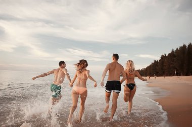 kumsalda, çalışan dört arkadaş yaz tatil ve mutluluk kavramı. Genç kadın denizde eğleniyor ve desteklemek