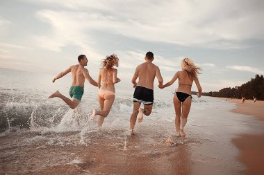 kumsalda, çalışan dört arkadaş yaz tatil ve mutluluk kavramı. Genç kadın denizde eğleniyor ve desteklemek