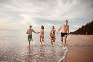 kumsalda, çalışan dört arkadaş yaz tatil ve mutluluk kavramı. Genç kadın denizde eğleniyor ve desteklemek