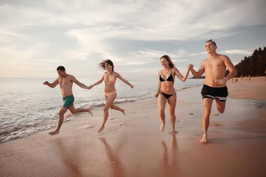 kumsalda, çalışan dört arkadaş yaz tatil ve mutluluk kavramı. Genç kadın denizde eğleniyor ve desteklemek