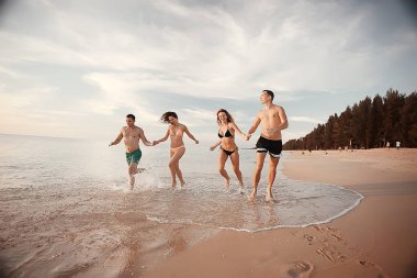 kumsalda, çalışan dört arkadaş yaz tatil ve mutluluk kavramı. Genç kadın denizde eğleniyor ve desteklemek