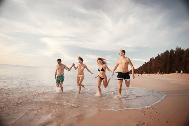 kumsalda, çalışan dört arkadaş yaz tatil ve mutluluk kavramı. Genç kadın denizde eğleniyor ve desteklemek