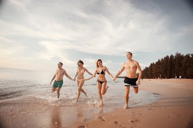 kumsalda, çalışan dört arkadaş yaz tatil ve mutluluk kavramı. Genç kadın denizde eğleniyor ve desteklemek