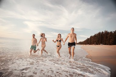 kumsalda, çalışan dört arkadaş yaz tatil ve mutluluk kavramı. Genç kadın denizde eğleniyor ve desteklemek