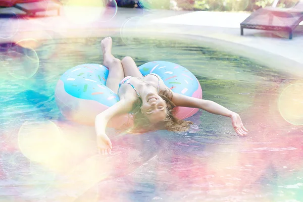 woman relaxing on inflatable ring in swimming pool