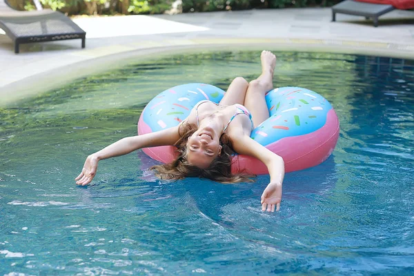 woman relaxing on inflatable ring in swimming pool