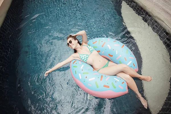 woman relaxing on inflatable ring in swimming pool