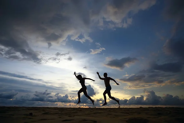 两名运动员沿着海滩奔跑的剪影 — 图库照片