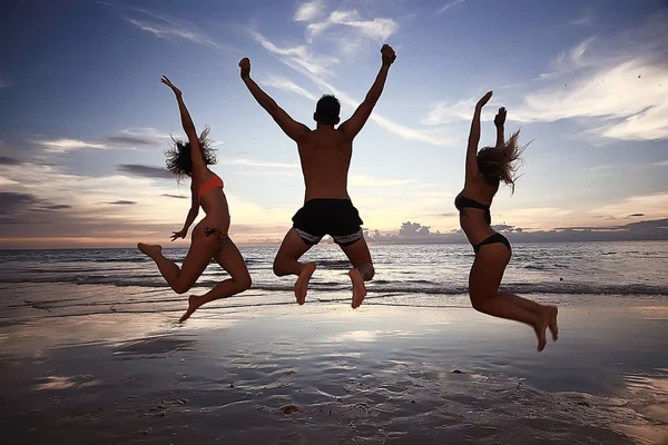 silhouettes of athletes jumping at the beach at sunset, healthy rest, sports activity, summer vacation