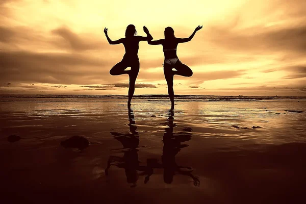 meditation and yoga on the beach. Two young women doing yoga on the sea shore