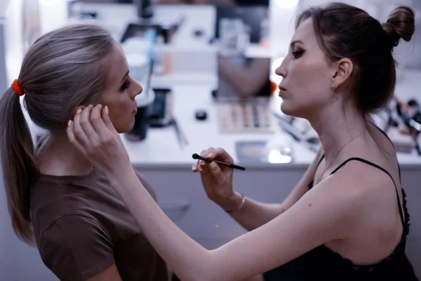 professional make-up in the beauty salon.  Master doing make-up for beautiful model in the salon