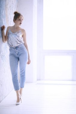 duvara yaslanmış poz ince kot giyen çekici genç kadın 