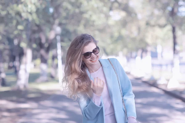 公園でスタイリッシュな青いコートを着ている金髪美人 — ストック写真