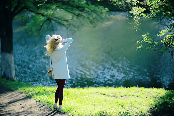Portrait of young woman looking at lake in spring park , back view