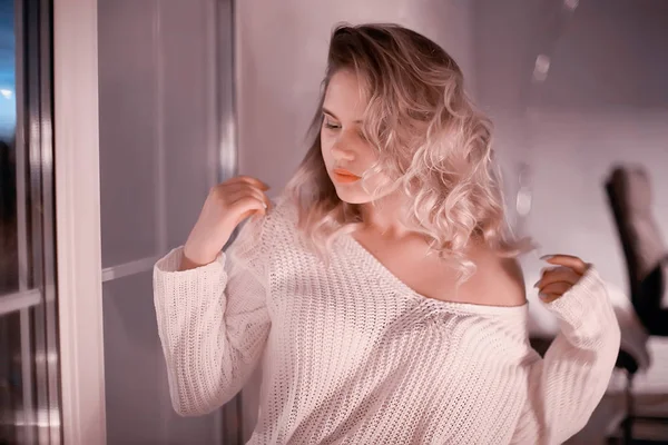 白いニットのセーター ポーズ自宅に若いブロンドの女性 — ストック写真