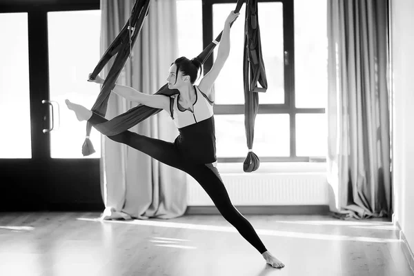 yoga in hammock. Sport and active lifestyle. Young female coach doing yoga in a hammock