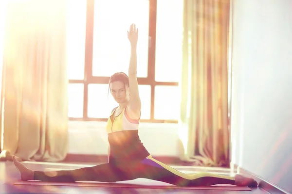 young and flexible woman doing yoga in gym