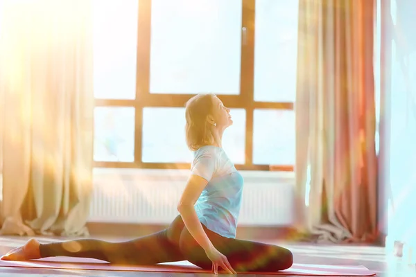 young and flexible woman doing yoga in gym