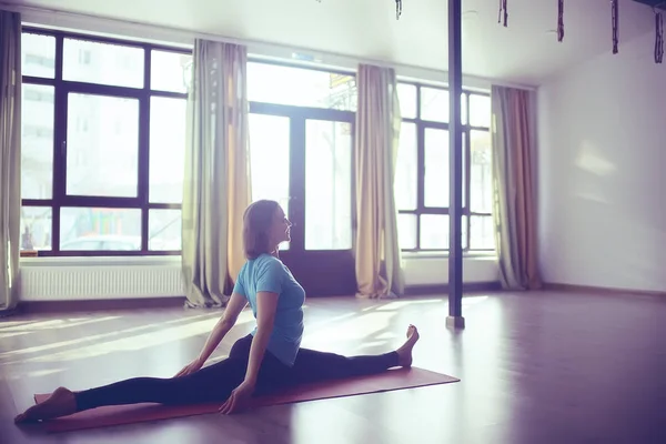 young and flexible woman doing yoga in gym