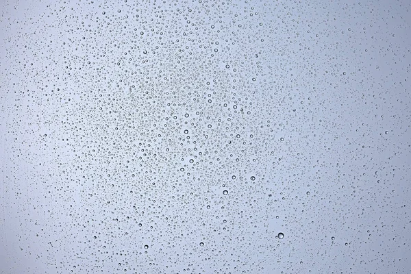 gray wet background, raindrops on window glass, concept of autumn weather