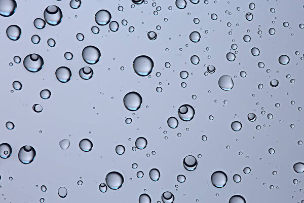 gray wet background, raindrops on window glass, concept of autumn weather