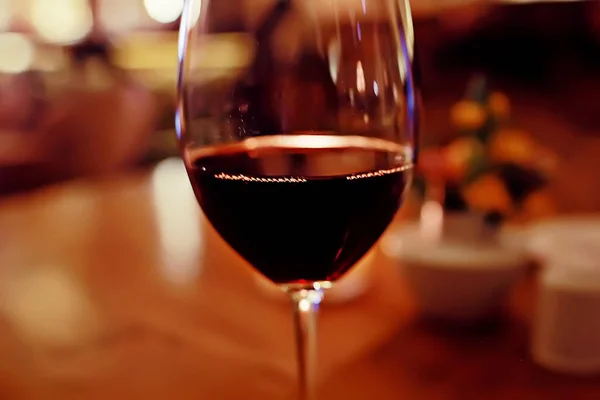 red wine glass serving / romantic dinner in the interior of the restaurant, a table served with a glass of grapes wine