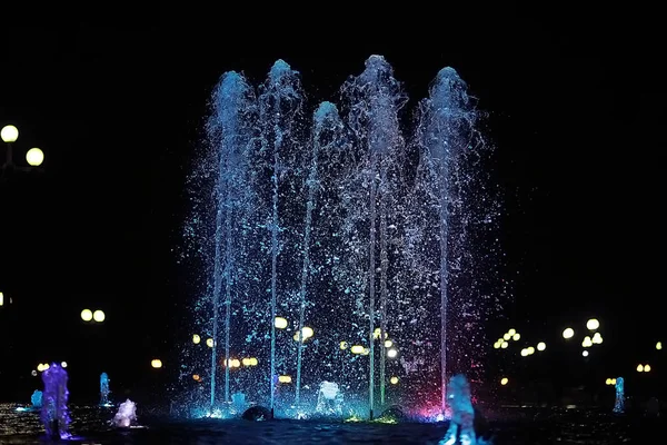 ジェット噴水で色水 街ではイルミネーションの — ストック写真