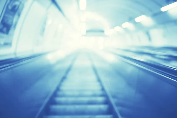 blurred background metro escalator / light blue background movement city infrastructure subway