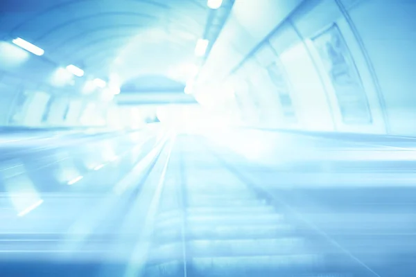 blurred background metro escalator / light blue background movement city infrastructure subway