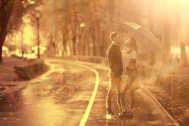 Sonbahar parkında güneş ışınları, aşık bir çift/genç adam ve kadın yürüyüş, güneşli parkın sonbahar görünümü, güneşin ışınları, sıcak sonbahar arka plan