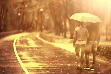 Sonbahar parkında güneş ışınları, aşık bir çift/genç adam ve kadın yürüyüş, güneşli parkın sonbahar görünümü, güneşin ışınları, sıcak sonbahar arka plan