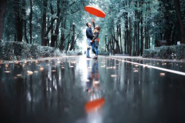 Sonbahar parkında yağmur/genç 25 yaşında çift adam ve kadın ıslak yağmurlu havalarda bir şemsiye altında yürümek, Ekim severler yürümek