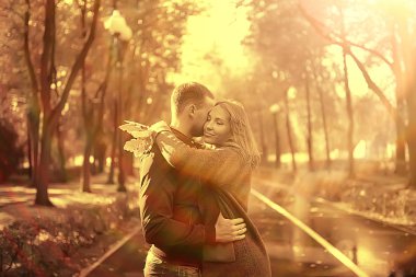 Sonbahar parkında güneş ışınları, aşık bir çift/genç adam ve kadın yürüyüş, güneşli parkın sonbahar görünümü, güneşin ışınları, sıcak sonbahar arka plan