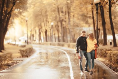 Sonbahar parkında güneş ışınları, aşık bir çift/genç adam ve kadın yürüyüş, güneşli parkın sonbahar görünümü, güneşin ışınları, sıcak sonbahar arka plan