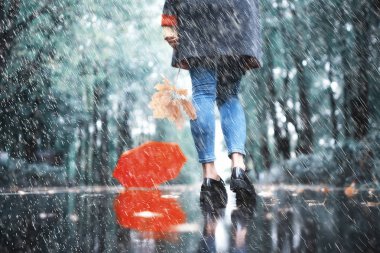 autumn landscape in the park girl with a red umbrella / concept autumn weather raining, a young woman under an umbrella