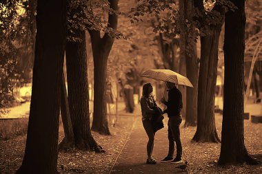 bir şemsiye altında iki kişi/bir erkek ve bir kadın bir şemsiye ile bir parkta yürüyüş, yağmur sonbaharda yürüyüş, bir sonbahar şemsiyesi