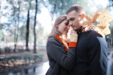 Sonbahar parkında güneş ışınları, aşık bir çift/genç adam ve kadın yürüyüş, güneşli parkın sonbahar görünümü, güneşin ışınları, sıcak sonbahar arka plan