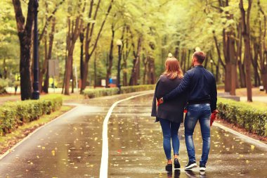 Sonbahar parkında güneş ışınları, aşık bir çift/genç adam ve kadın yürüyüş, güneşli parkın sonbahar görünümü, güneşin ışınları, sıcak sonbahar arka plan